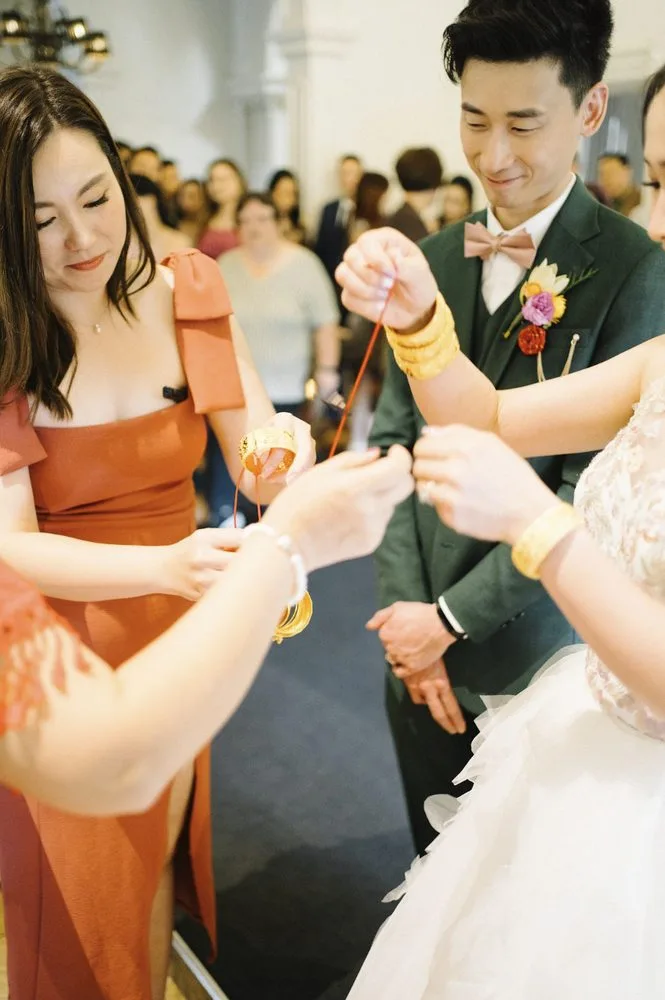 Bride and groom receiving gold bangles tied with red string at a Chinese wedding ceremony, Melbourne